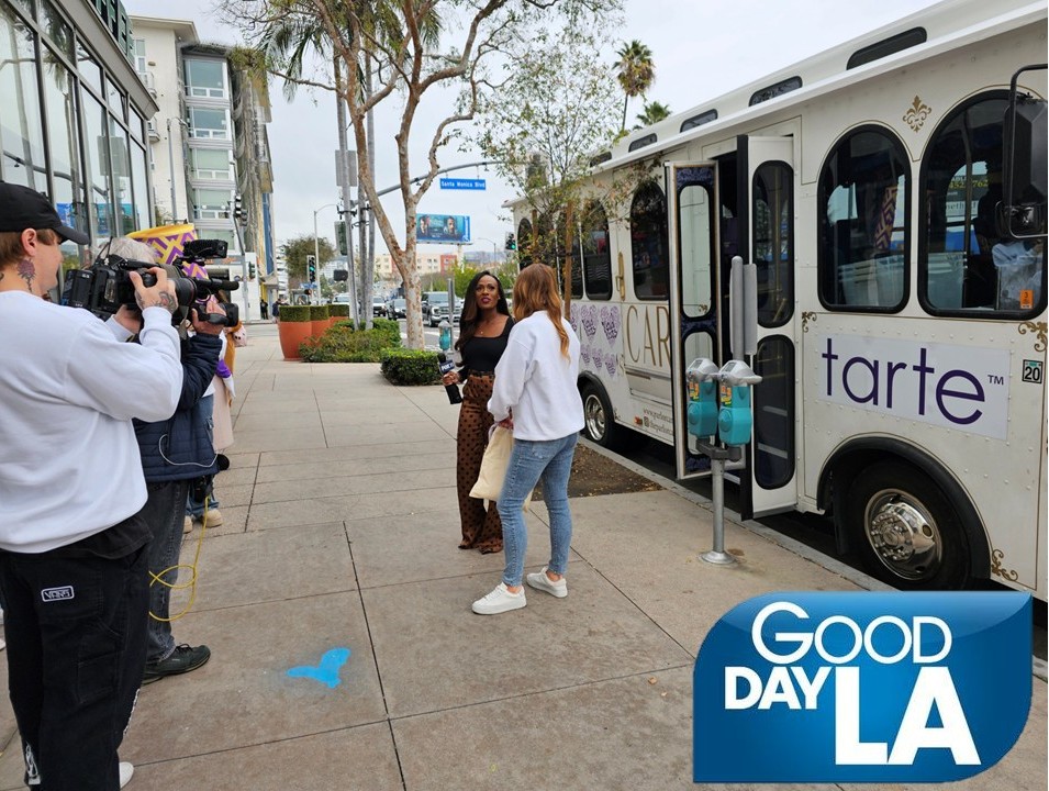 A group of guests standing next to a white Parlor Car Trolley being used as the Tarte Cosmetics Kindness Shuttle for a private brand activation in Hollywood.