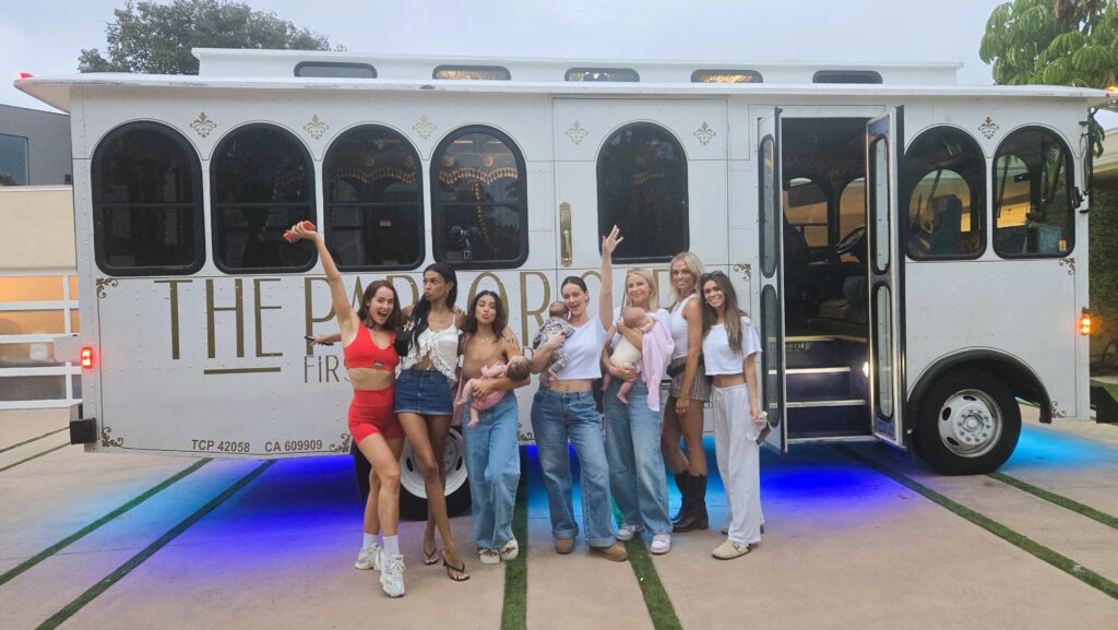 The cast of Hulu’s Secret Lives of Mormon Wives posing in front of a white Parlor Car Trolley with blue underglow lighting.