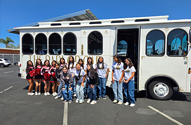 A white vintage-style Parlor Car Trolley with concerts & sports peoples infront