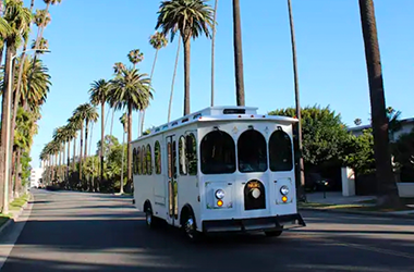 A white vintage-style Parlor Car Trolley on road for private event transportation