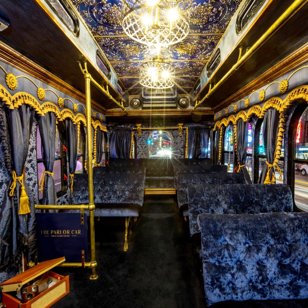 Opulent interior of the Parlor Car Trolley featuring navy blue velvet seats, ornate gold trim, and decorative ceiling details.